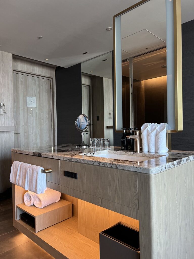 Salle de bain moderne de l'Autograph Osaka avec comptoir en marbre et miroir rétroéclairé