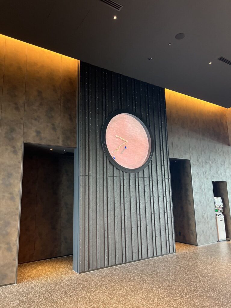 Hall d'entrée de l'Autograph Osaka avec grande horloge circulaire et design moderne en bois
