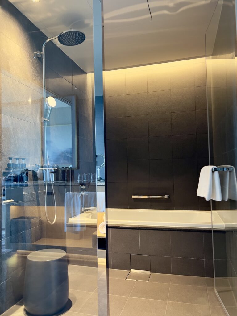 Salle de bain luxueuse de l'Autograph Osaka avec douche en marbre et verrière moderne