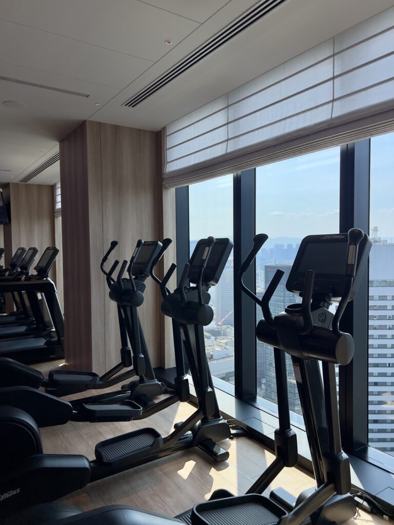 Salle de fitness de l'Autograph Osaka avec équipements et vue panoramique sur la ville d'Osaka