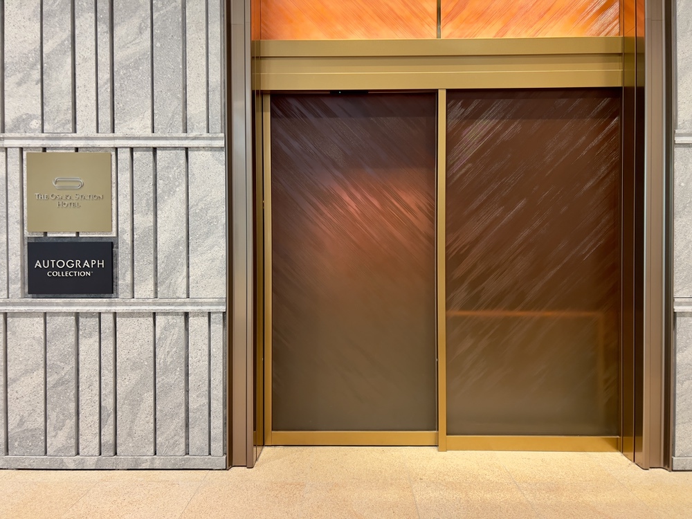 Entrée moderne de l'Autograph Osaka avec portes dorées et signalétique élégante sur façade en pierre