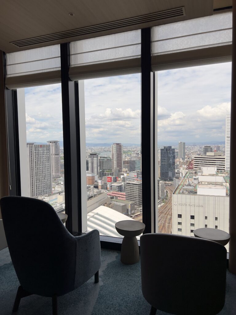 Salon de suite executive du Autograph Osaka avec table ronde, lustre design et vue panoramique sur la métropole