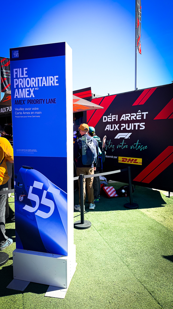 File prioritaire Amex pour l'accès privilégié au paddock F1 avec signalétique bilingue et activité défi arrêt aux puits