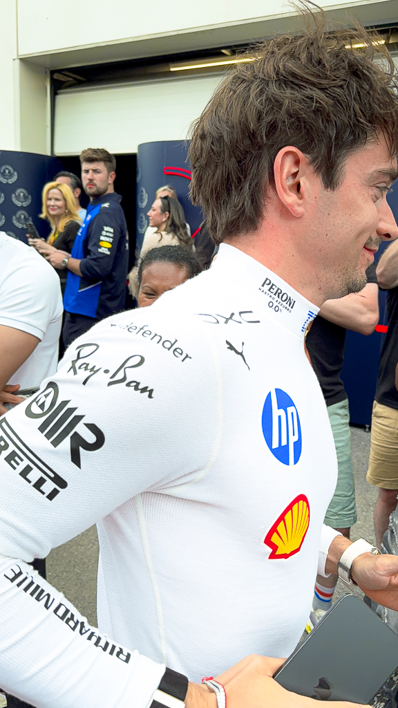 Pilote F1 signant sa combinaison Mercedes avec logos sponsors dans le paddock de Montreal