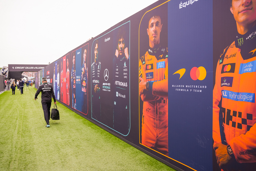 Mur d'exposition montrant les portraits des pilotes F1 et leurs écuries au paddock de Montreal