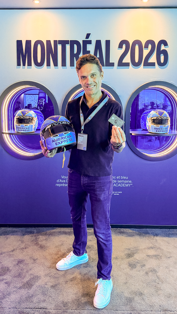 Invité tenant des casques F1 commémoratifs devant l'affichage Montreal 2026 dans l'espace Amex