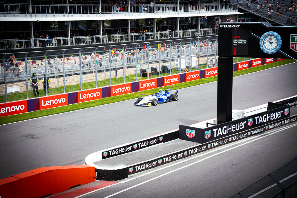 Monoplace F1 bleue et blanche en action sur le circuit Gilles-Villeneuve de Montréal avec tribunes et sponsoring visible