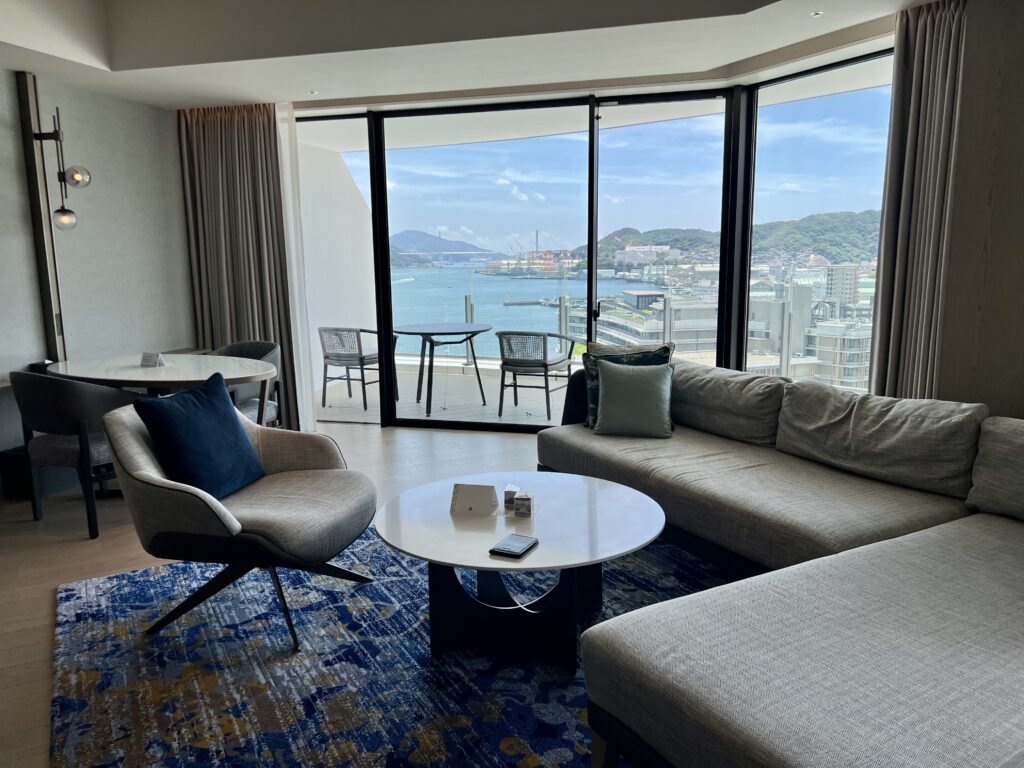 Suite moderne du marriott nagasaki avec salon, télévision intégrée et écran Marriott Bonvoy pour services hôteliers