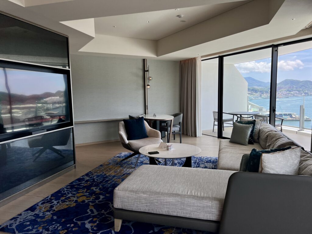 Salon spacieux d'une suite du marriott nagasaki avec télévision grand écran et vue panoramique sur la baie