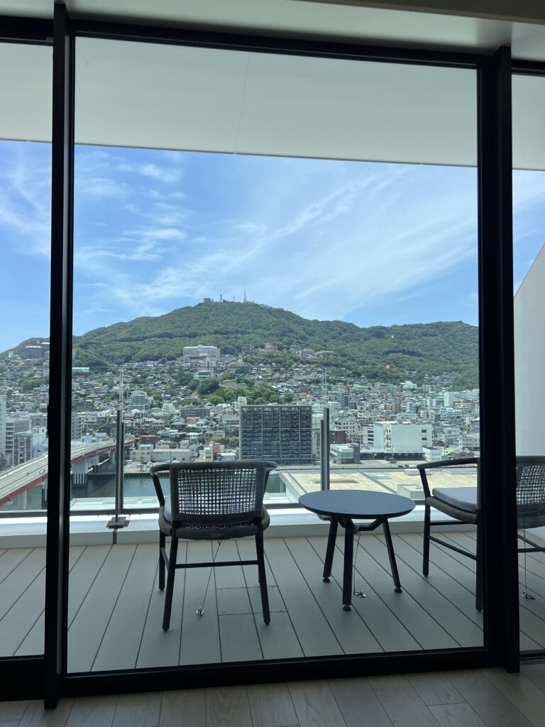Vue sur les montagnes verdoyantes de Nagasaki depuis la terrasse d'une suite du marriott nagasaki avec mobilier moderne