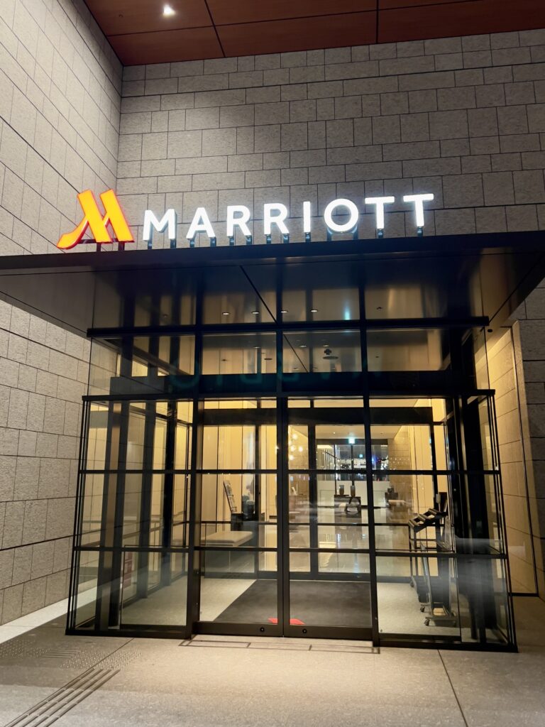 Entrée principale illuminée du marriott nagasaki de nuit avec logo éclairé et façade moderne en pierre