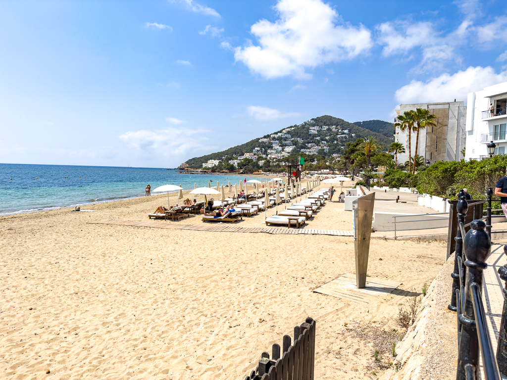 Plage de Santa Eulalia avec transats prives du w ibiza et vue sur les collines verdoyantes d'Ibiza