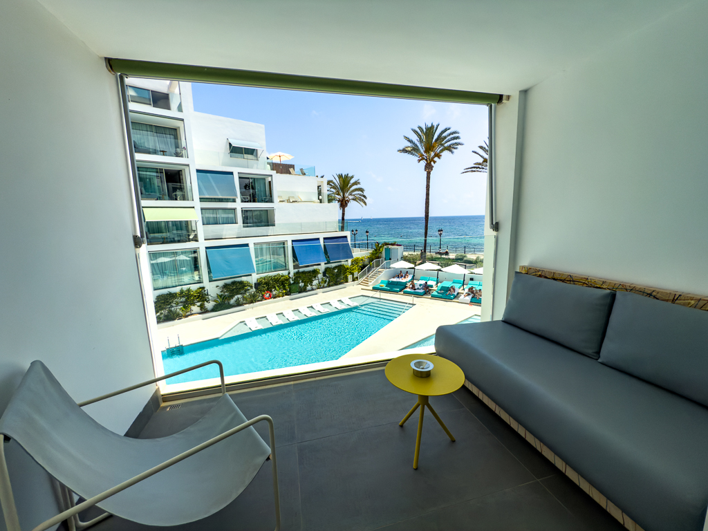 Salon d'une suite du w ibiza avec vue panoramique sur la piscine, palmiers et mer Méditerranée