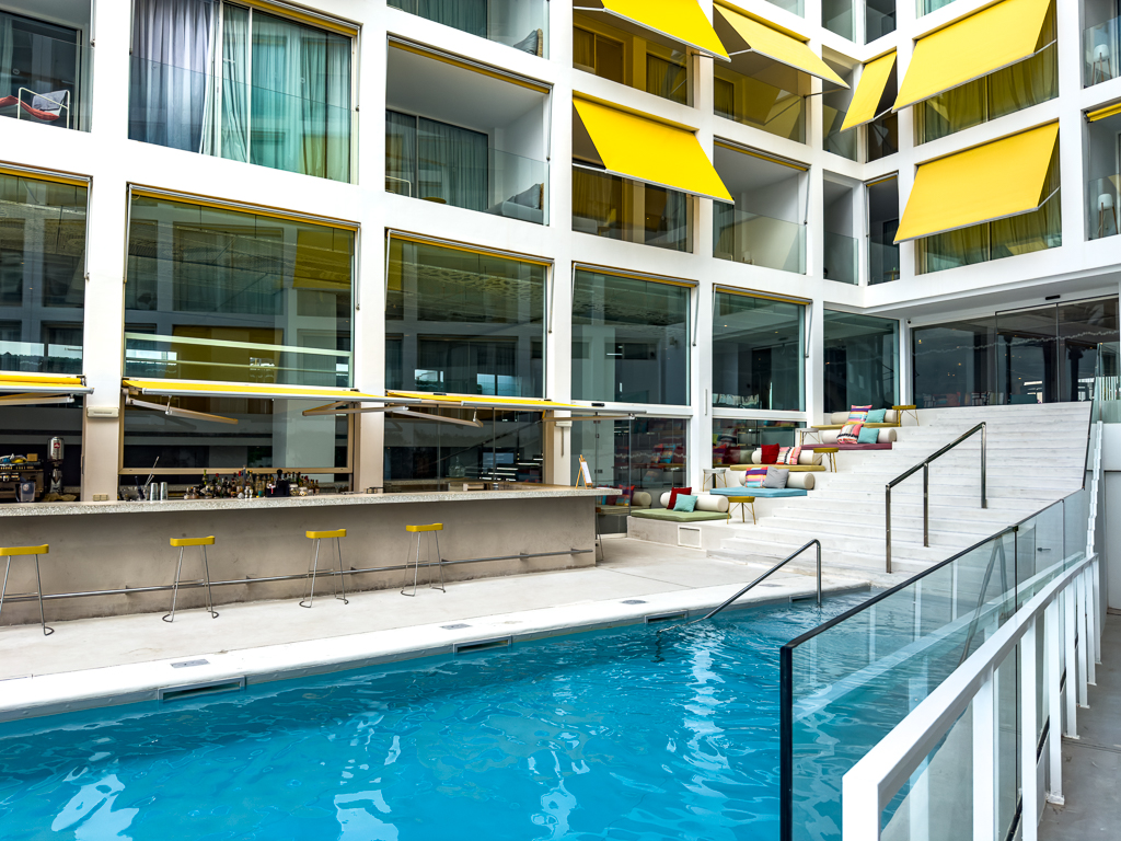 Piscine interieure du w ibiza dans un courtyard moderne avec bar aquatique et parasols jaunes