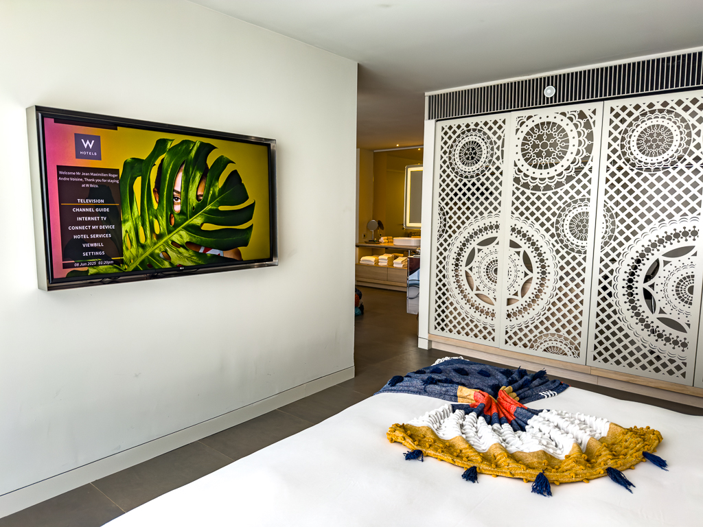 Chambre du w ibiza avec télévision murale, cloisons décoratives blanches et textiles aux couleurs vives