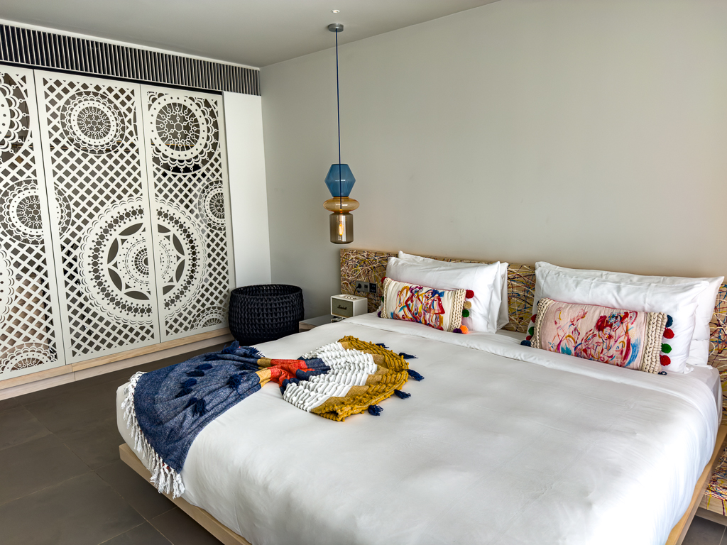 Chambre du w ibiza avec cloisons ajourées blanches motifs géométriques et linge coloré sur le lit