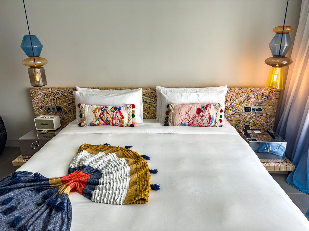 Chambre du w ibiza avec lit double, tête de lit en osier tressé et suspensions colorées design