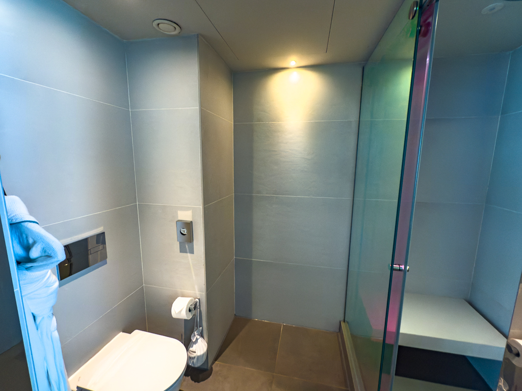Salle de bain moderne du w ibiza avec douche à l'italienne, carrelage gris et éclairage contemporain