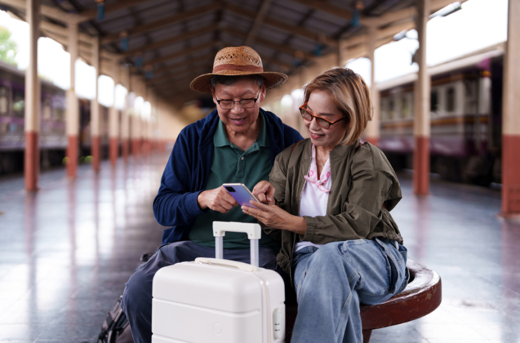 couple sitting down with suitcase looking at phone
