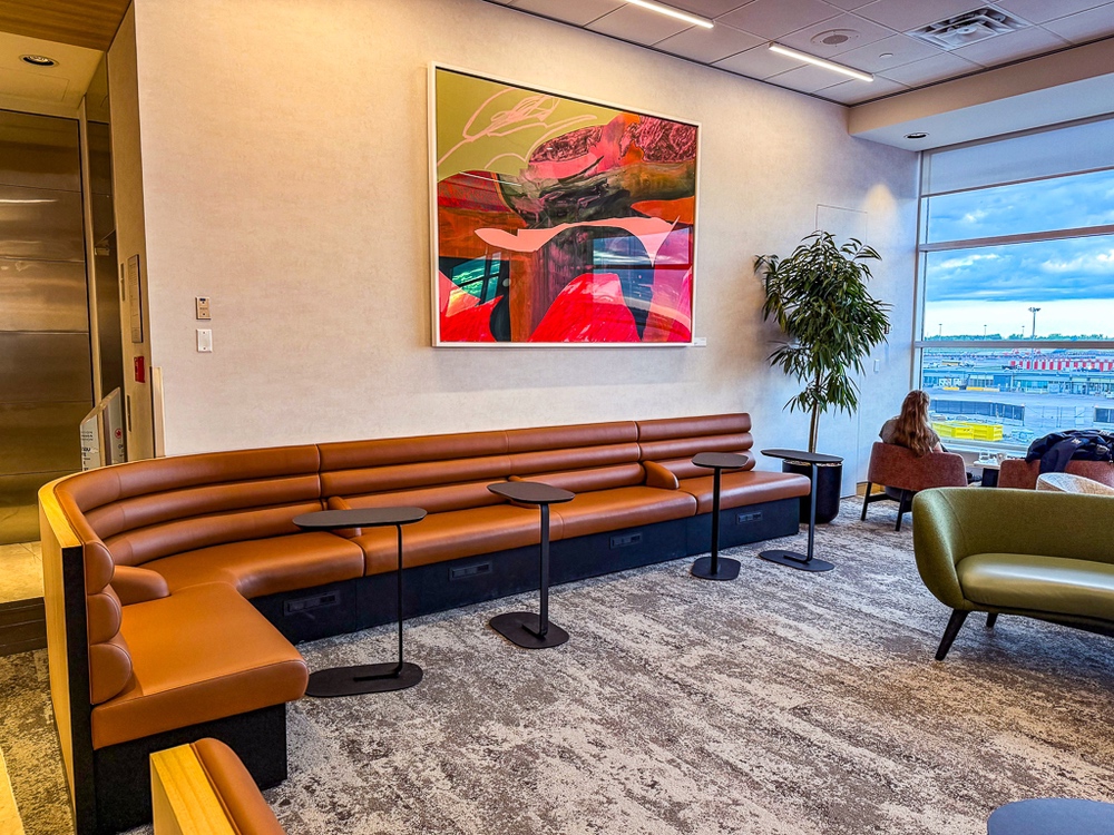 Banquette en cuir orange du salon air canada avec œuvre d'art contemporaine colorée accrochée au mur beige