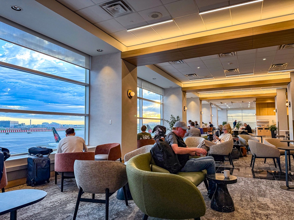 Atmosphère détendue du salon air canada avec voyageurs installés dans fauteuils modernes sous éclairage chaleureux