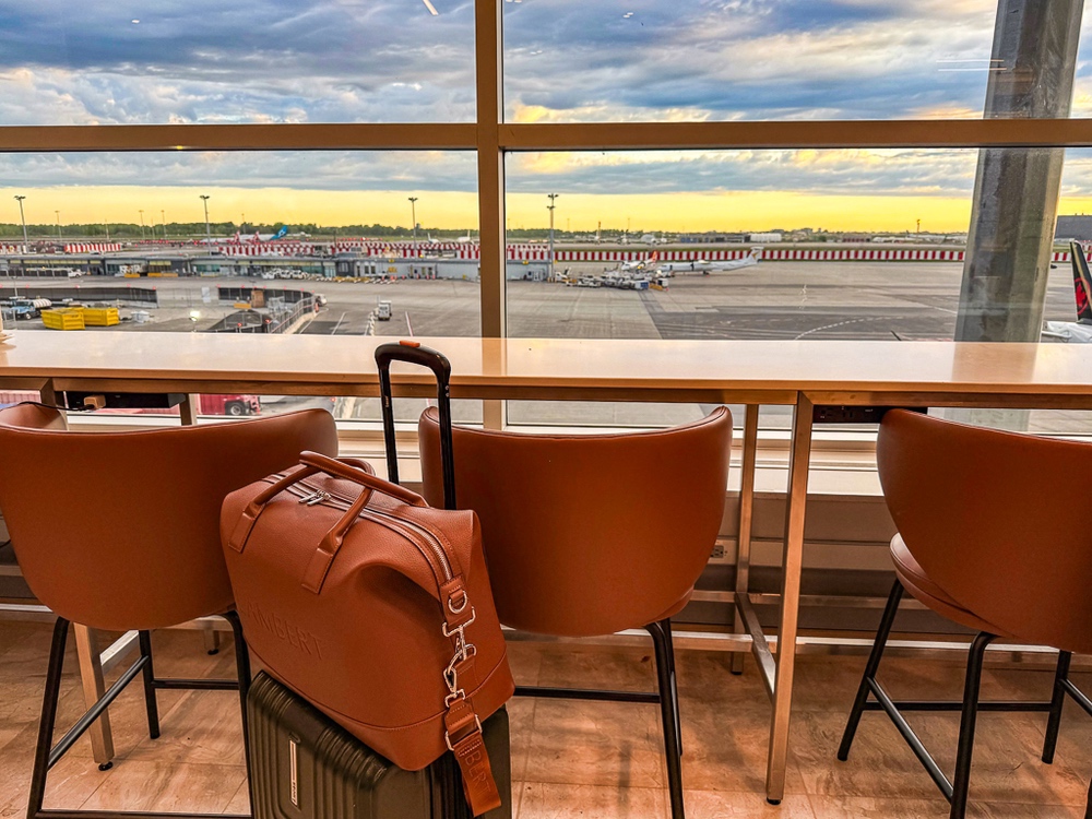 Sièges en cuir orange face aux baies vitrées du salon air canada avec vue directe sur les avions et pistes