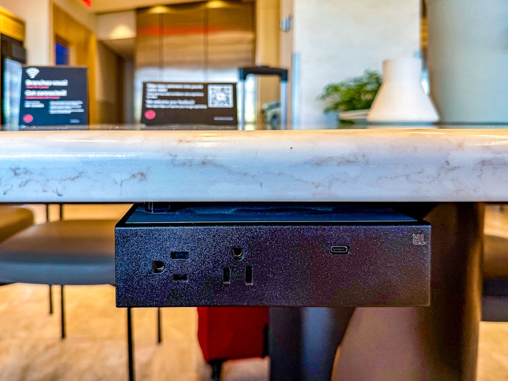Prises électriques et ports USB intégrés sous le comptoir en marbre du salon air canada pour recharger appareils