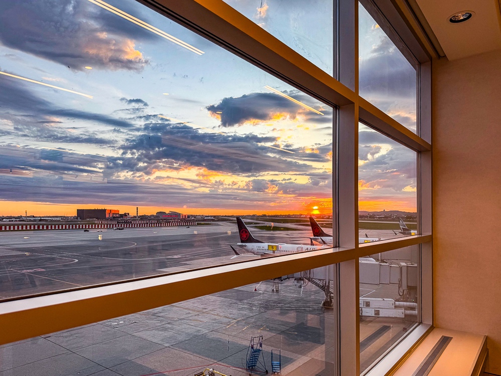 Vue spectaculaire sur les pistes d'aeroport au coucher du soleil depuis les grandes fenetres du salon air canada
