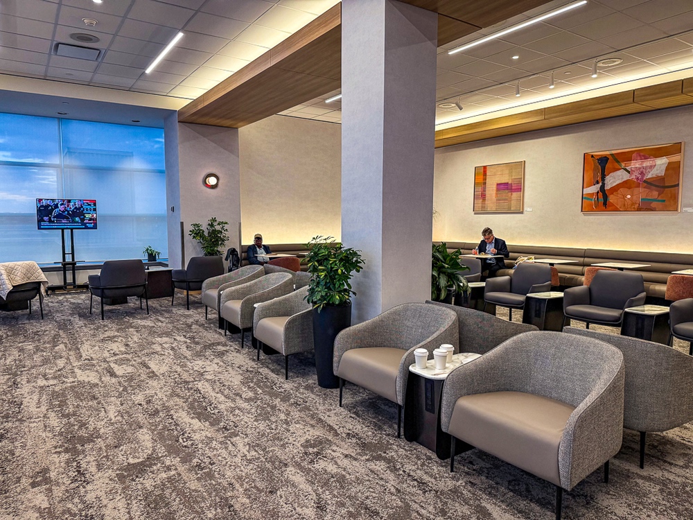 Vue d'ensemble du salon air canada montrant l'aménagement moderne avec fauteuils neutres et décoration artistique murale