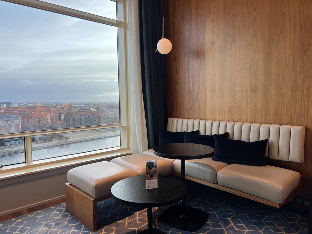 Banquette et petites tables devant la fenêtre panoramique de la chambre