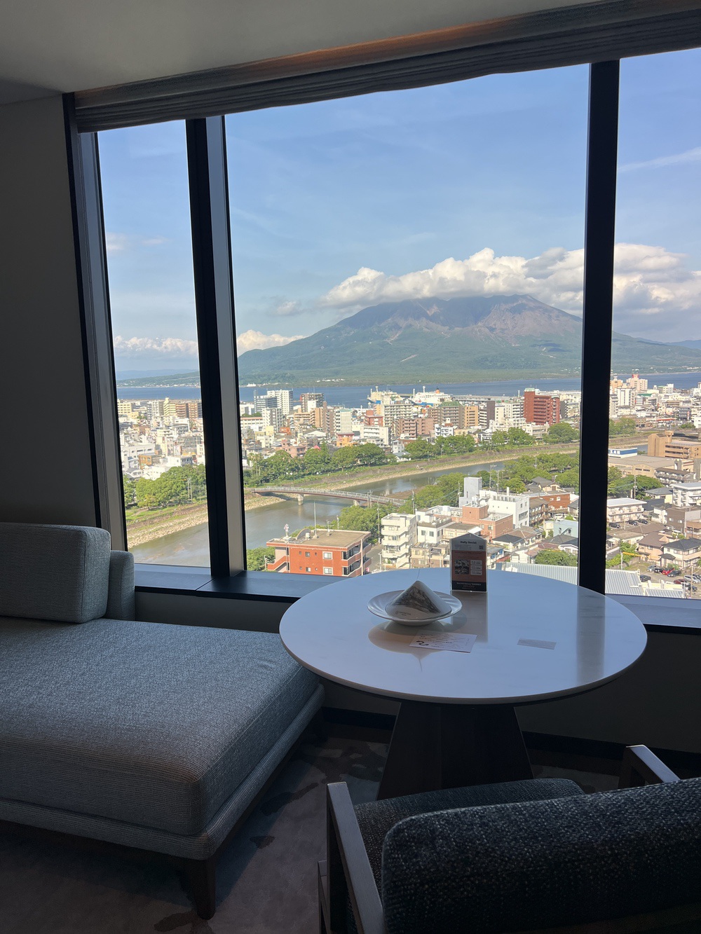 Coin table et banquette face à la baie vitrée, vue sur le Sakurajima