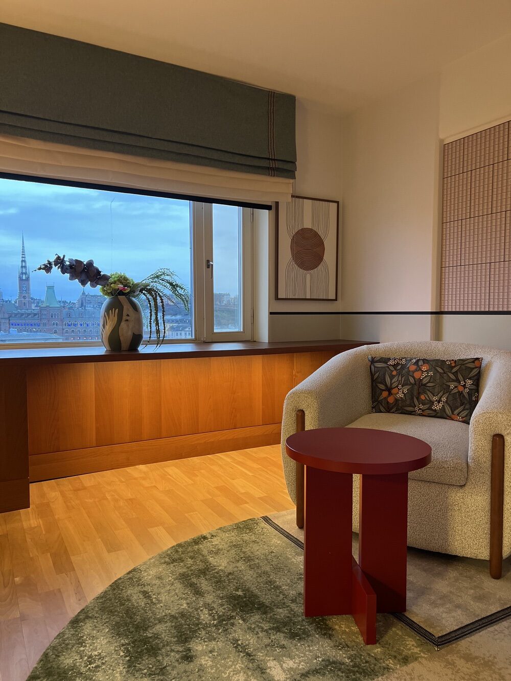 Coin salon de la suite avec fauteuil bouclé et vue sur Stockholm