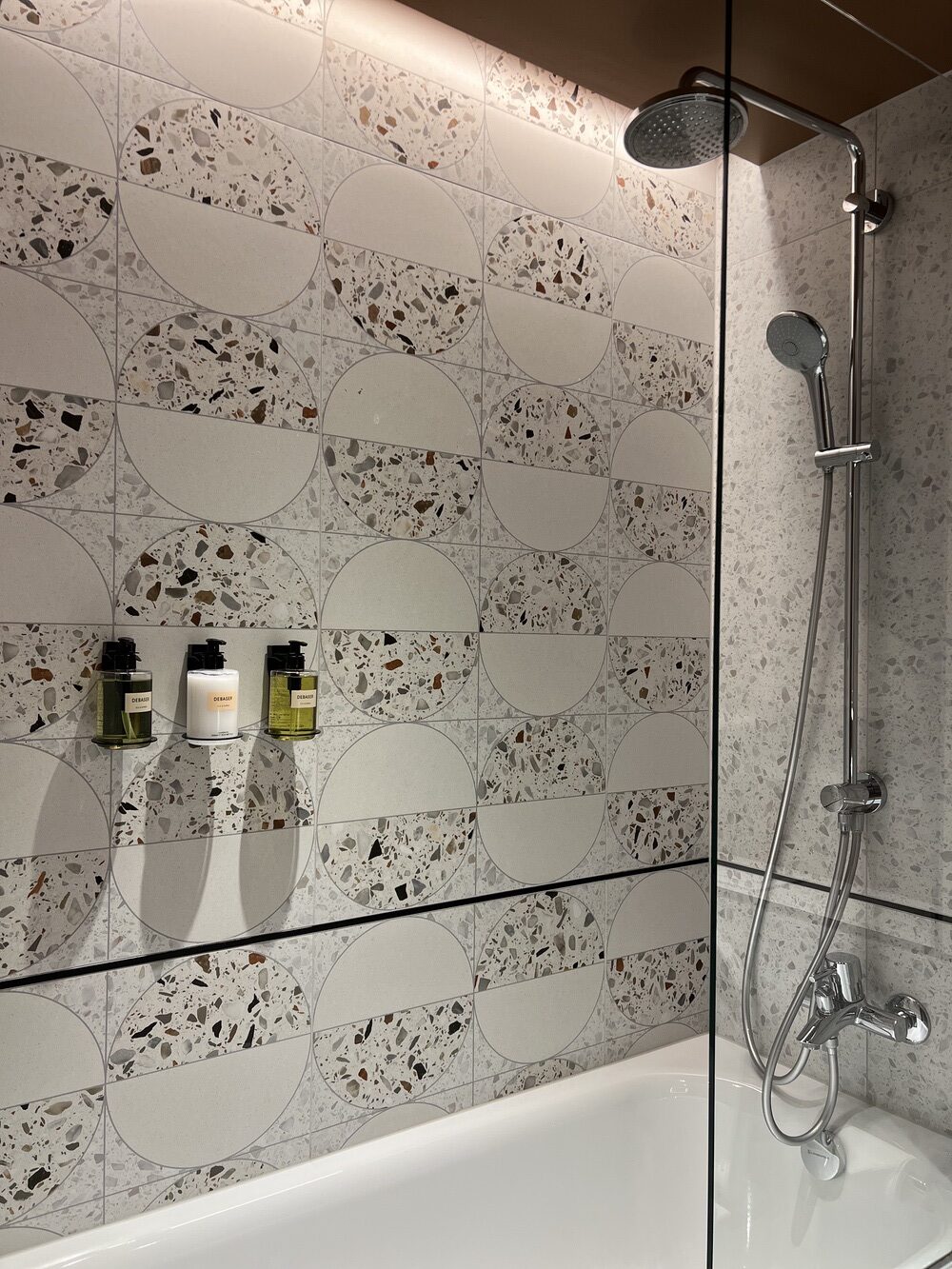 Salle de bain en terrazzo avec baignoire et produits Debaser
