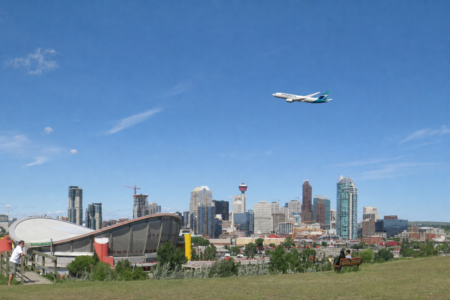 Avion WestJet survolant le centre-ville de Calgary, avec la Tour de Calgary et le Saddledome