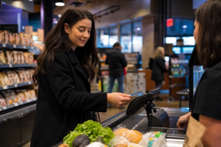 Woman paying for her grocery purchases with a credit card at the checkout