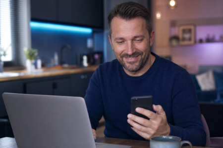 Homme vérifiant son score de crédit sur son téléphone et ordinateur portable