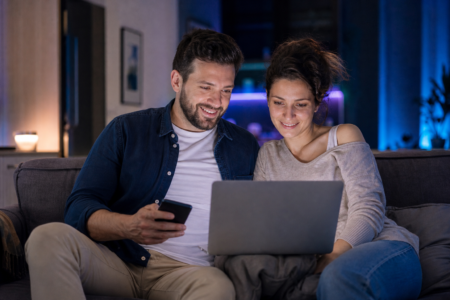 Couple utilisant un ordinateur portable et un téléphone à la maison pour gérer ses points RBC Avion sans voyager