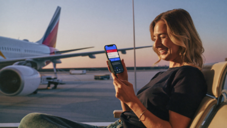 Traveler in an airport lounge checking her phone for a Chase Ultimate Rewards to Aeroplan points transfer
